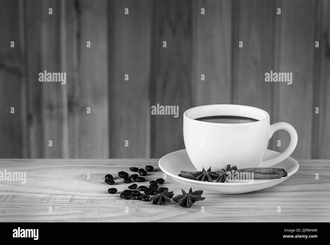 Kaffeetasse und Kaffeebohnen auf Holztischhintergrund.Schwarz-Weiß-Ton Stockfoto