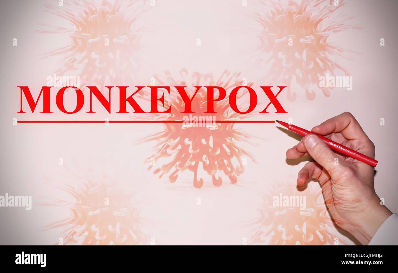 Hand eines Arztes, der das Wort „Monkeypox“ mit der Bakterienzelle als Hintergrund schreibt. Konzept des Virus. Stockfoto