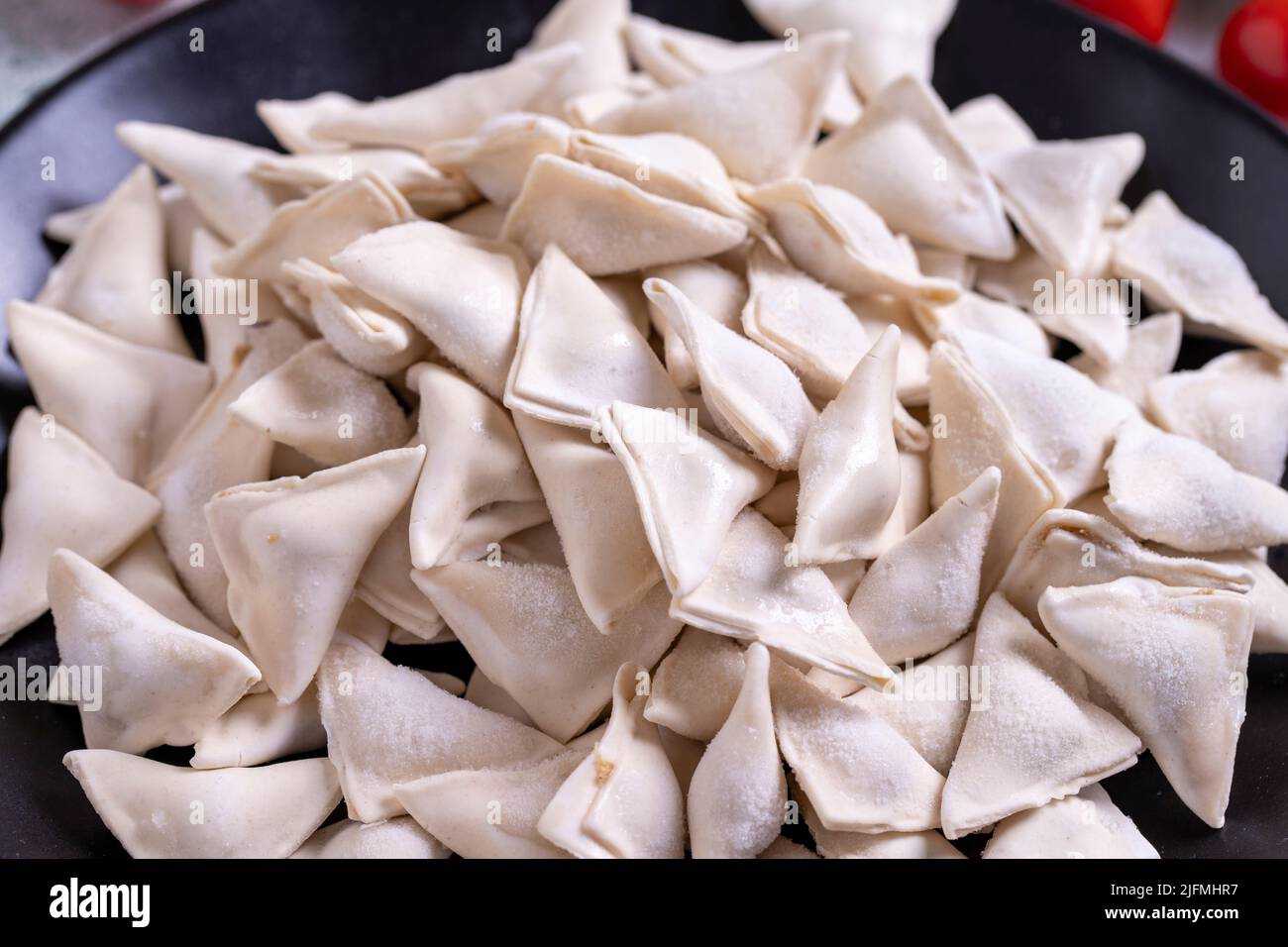 Gefrorene Ravioli auf Steinboden. Gefüllte Ravioli in der Mitte. Türkische Ravioli. Traditionelle Köstlichkeiten der Weltküche. Nahaufnahme. Stockfoto