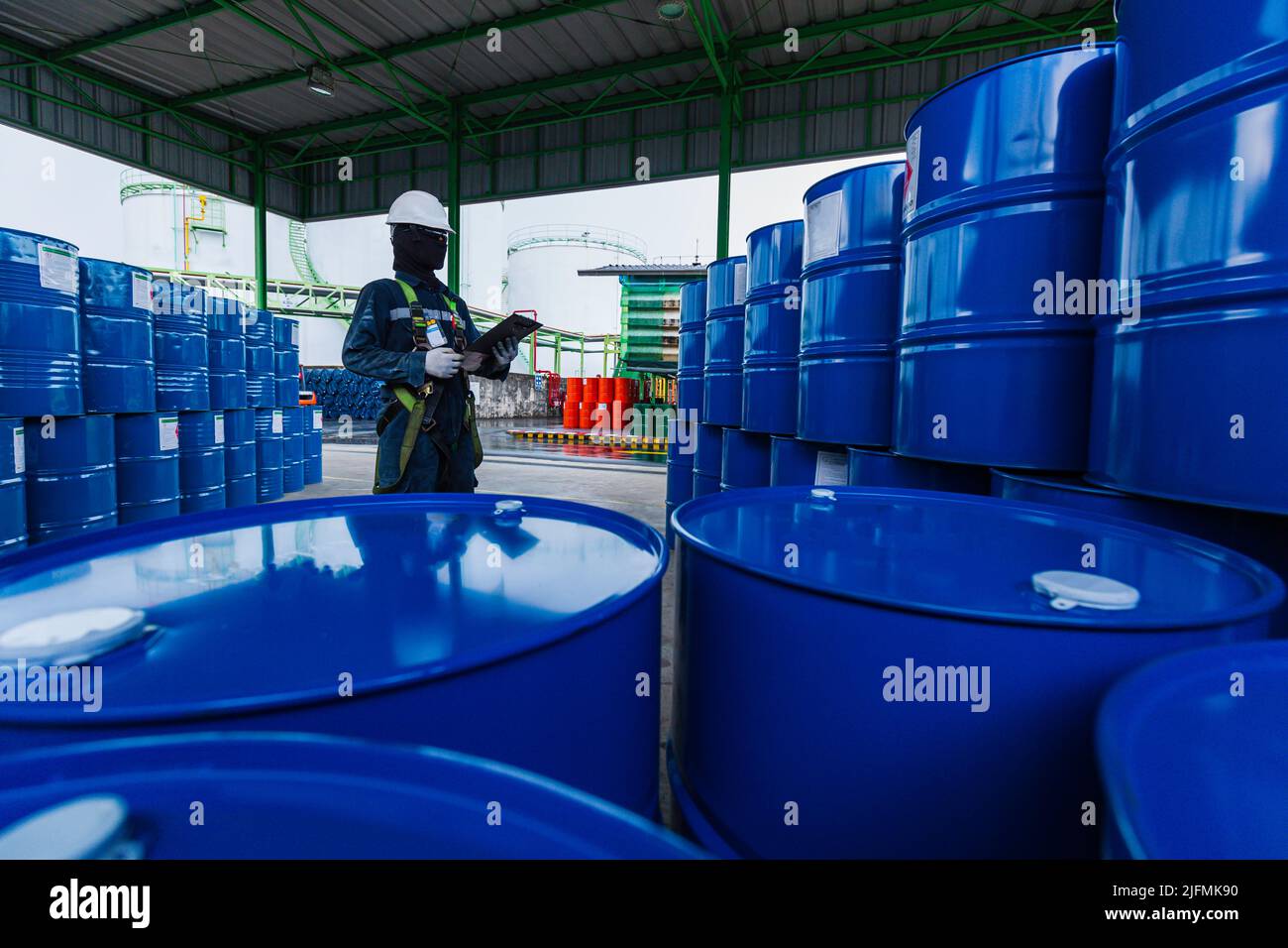 Männliche Arbeiter Inspektion Rekord Fass Öl Lager Fässer blau vertikal oder chemisch für in der Industrie. Stockfoto