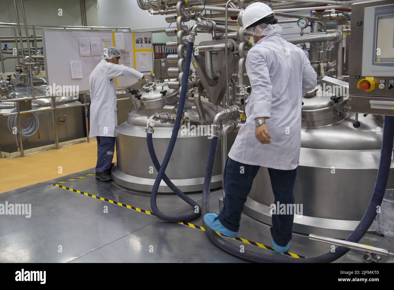 Männliche zwei arbeiten den Prozess der kosmetischen Creme Fermentation bei der Herstellung mit Edelstahl-Tank auf dem Hintergrund Stockfoto