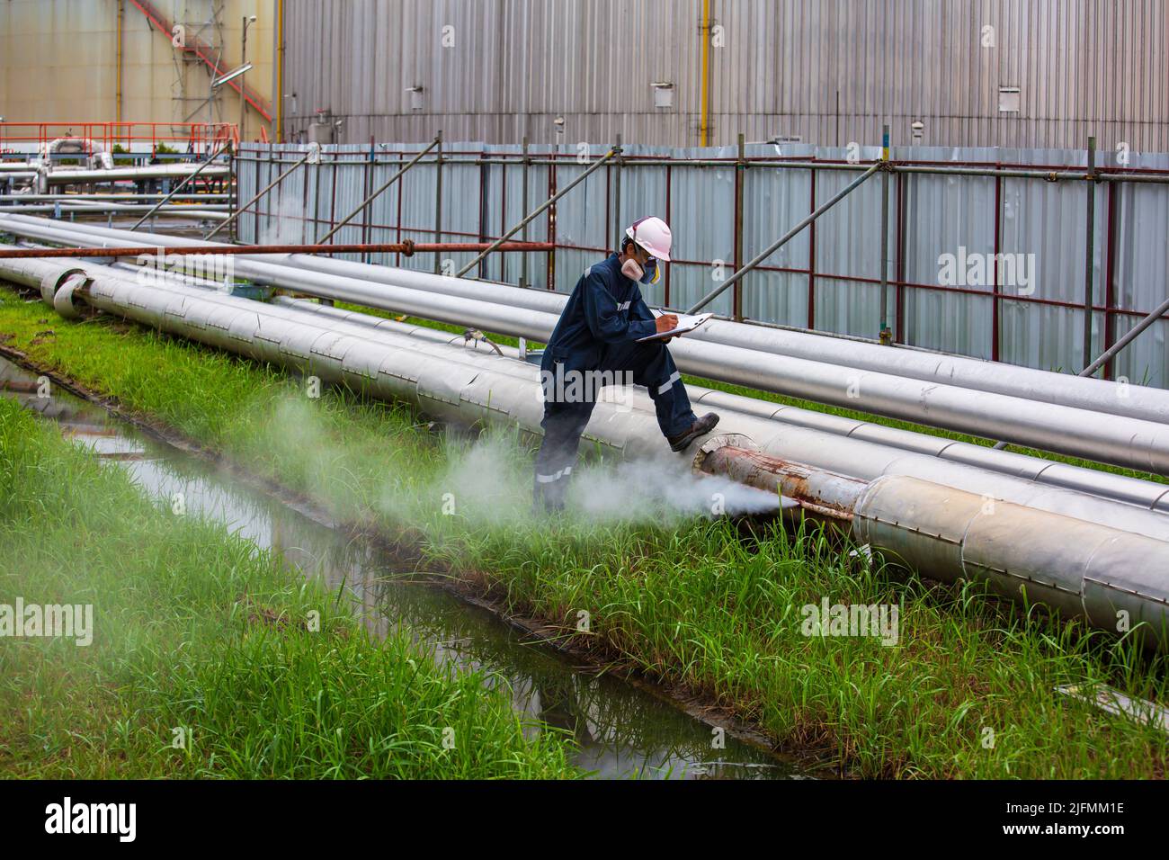 Männlicher Arbeiter Inspektion Sichtleitung Öl und Gas Korrosion Rost durch Steckrohr Dampfgas Leckleitung an der Isolierung. Stockfoto