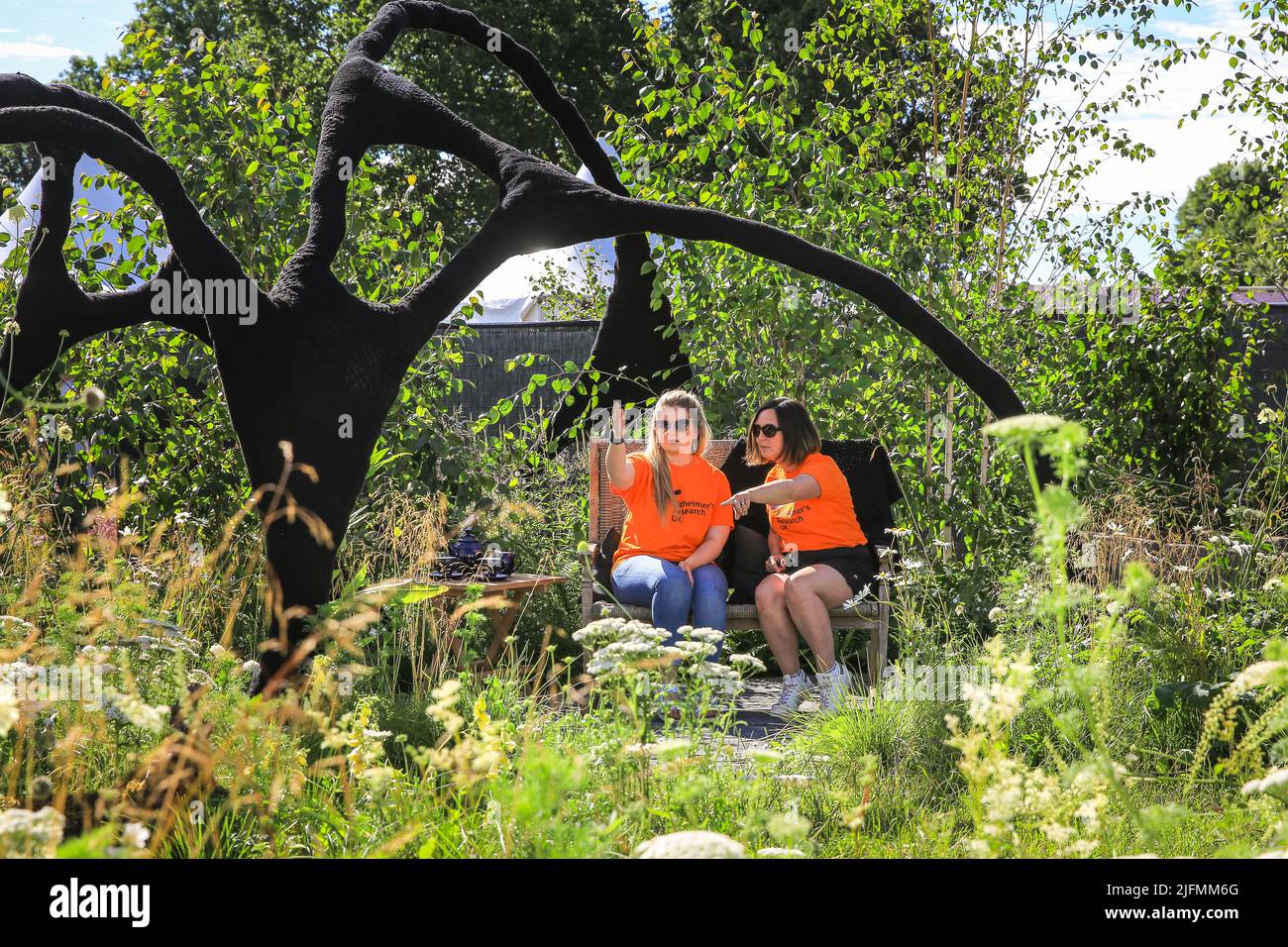 Hampton Court, London, Großbritannien. 04.. Juli 2022. Freiwillige sitzen im „Connections“-Garten der Alzheimer-Gesellschaft in einem schönen Raum mit Wildblumen, die die sich verändernde Dynamik in einer Familie oder Gruppe veranschaulichen. Presseinformungstag beim RHS Hampton Court Palace Garden Festival (ehemals Hampton Court Flower Show). Kredit: Imageplotter/Alamy Live Nachrichten Stockfoto