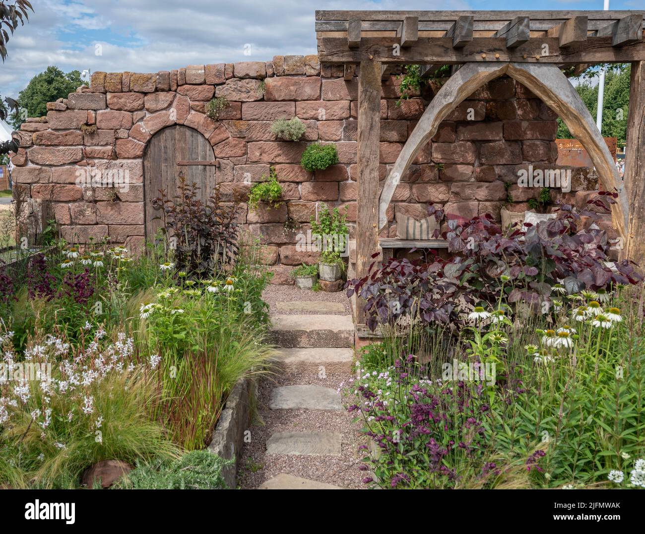 Hampton Court Palace, Surrey, Großbritannien. 4. Juli 2022. RHS Hampton Court Palace Garden Festival Pressetag für die größte Blumenschau der Welt, die bis zum 9. Juli 2022 stattfindet. Bild: Global Impact Garden: Der wunderschöne Garten der Blue Diamond Group, der vom Team der Blue Diamond Group entworfen wurde, soll die Besucher mit seinem Gefühl von Romantik und schöner Verlassenheit begeistern. Ein stillgebliebenes Bauerngebäude hat im Garten Spuren hinterlassen. Quelle: Malcolm Park/Alamy Live News Stockfoto