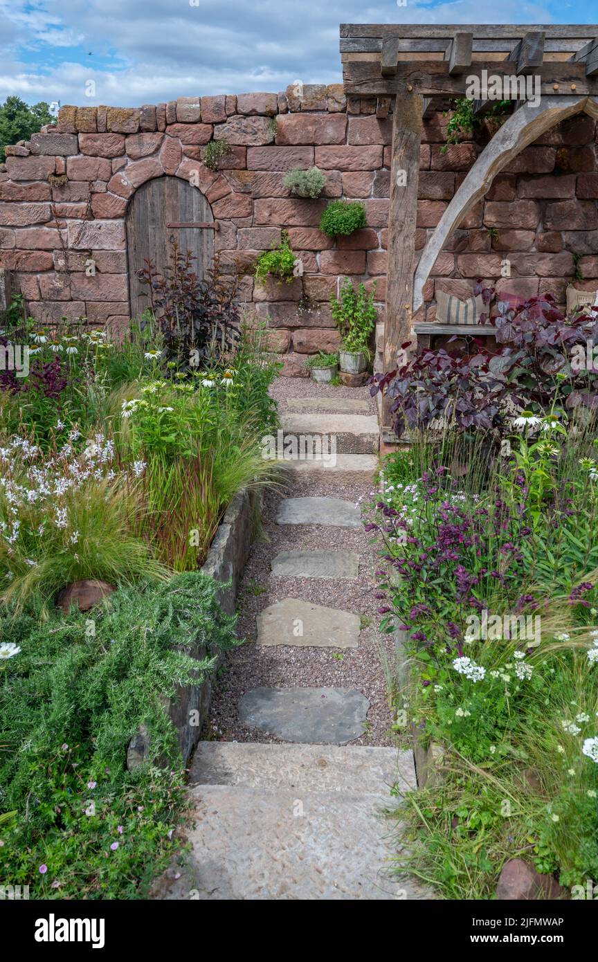 Hampton Court Palace, Surrey, Großbritannien. 4. Juli 2022. RHS Hampton Court Palace Garden Festival Pressetag für die größte Blumenschau der Welt, die bis zum 9. Juli 2022 stattfindet. Bild: Global Impact Garden: Der wunderschöne Garten der Blue Diamond Group, der vom Team der Blue Diamond Group entworfen wurde, soll die Besucher mit seinem Gefühl von Romantik und schöner Verlassenheit begeistern. Ein stillgebliebenes Bauerngebäude hat im Garten Spuren hinterlassen. Quelle: Malcolm Park/Alamy Live News Stockfoto