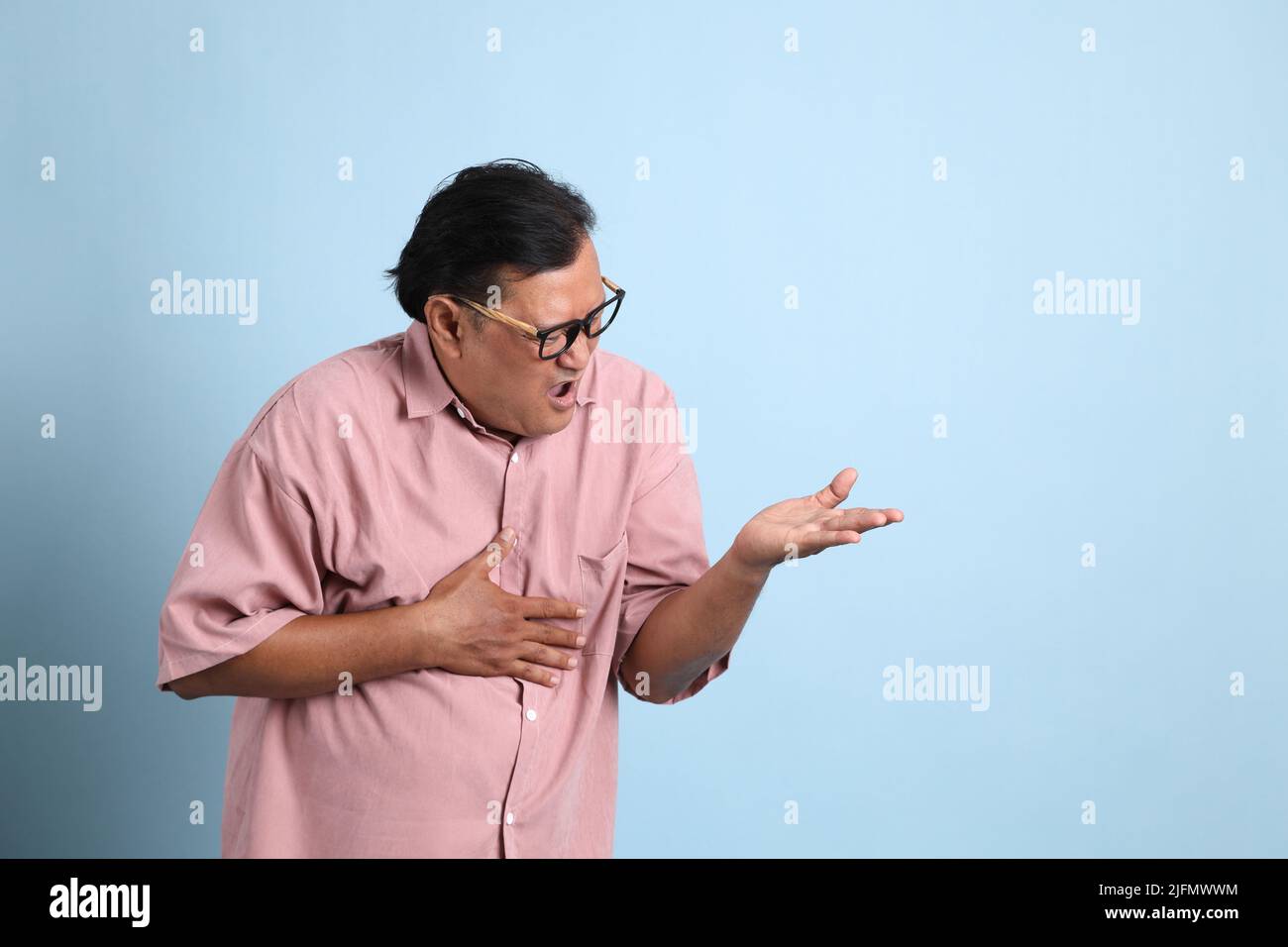 Der Erwachsene asiatische Mann mit rosa Hemd auf dem blauen Hintergrund stehen. Stockfoto