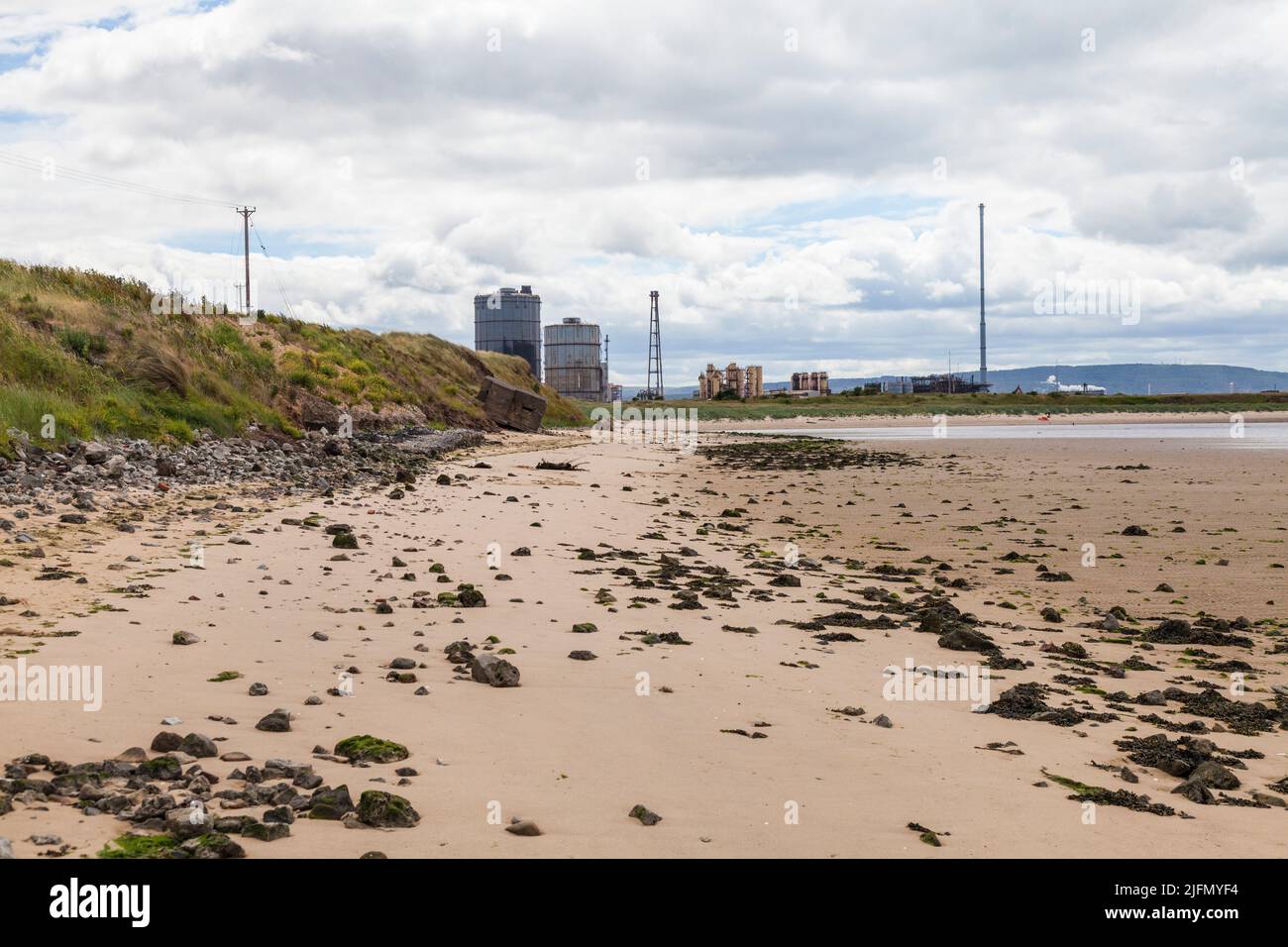 Ein Blick entlang des Strandes von Redcar, England, Großbritannien mit den ehemaligen Stahlwerken im Hintergrund Stockfoto