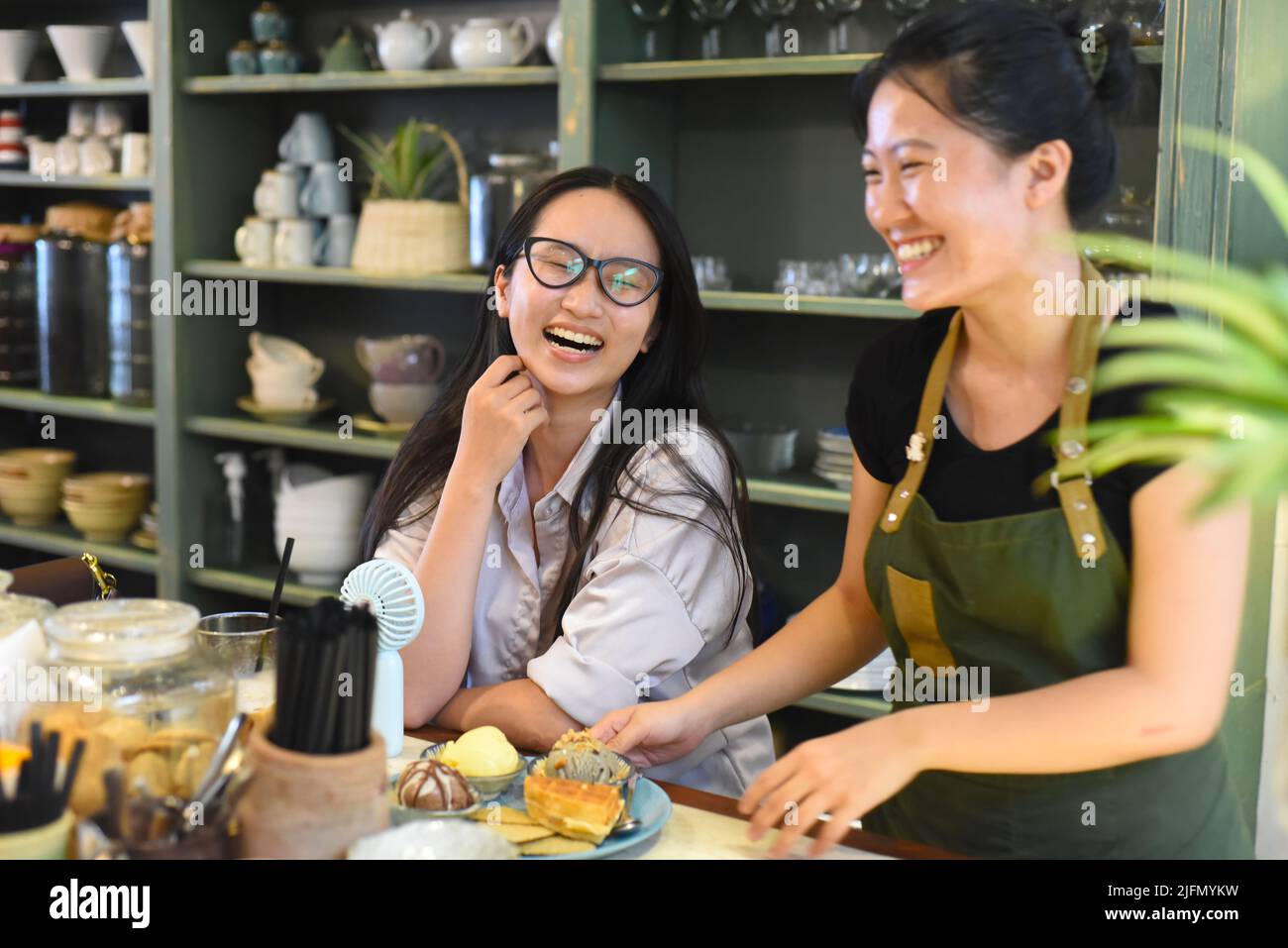 Lächelnde vietnamesische Kellnerin serviert ein Eis mit Waffeln im vietnamesischen Café Stockfoto