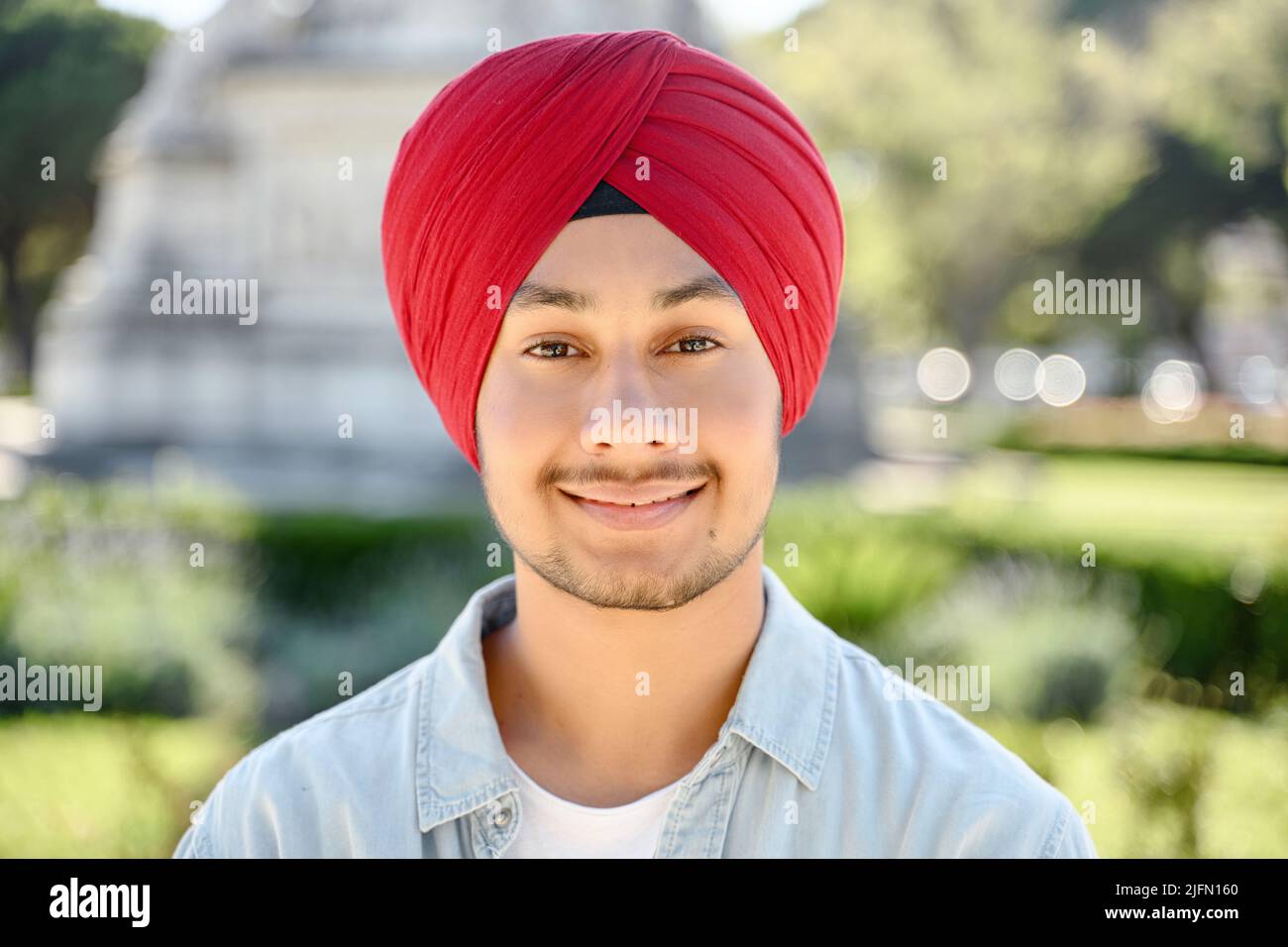 Der junge, gutaussehende sikh-Typ in traditionellem Kopftuch-Turban blickt auf die Kamera und lächelt, Nahaufnahme-Porträt eines glücklichen indischen Studenten, Unternehmers, der draußen steht Stockfoto