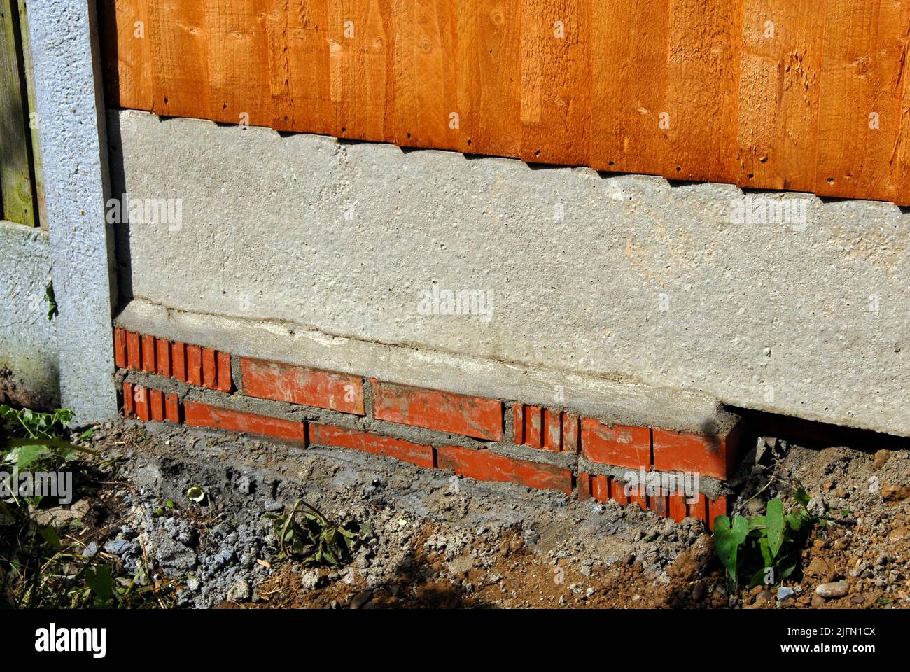 Einzäunung zwischen Gärten in einem Bereich mit welligen Bodenebenen und schlechten Mauerwerk Stockfoto
