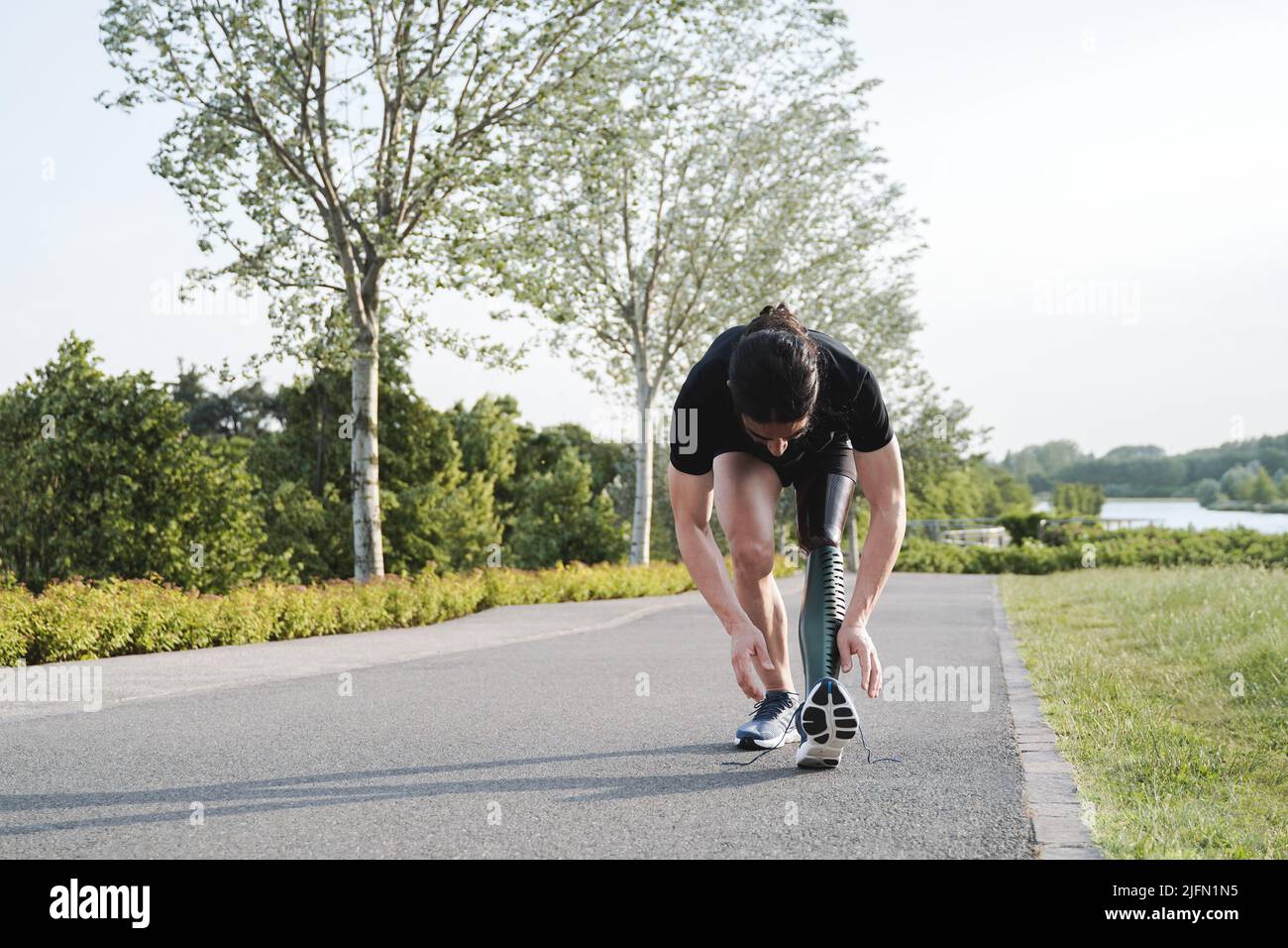 Sportmann mit körperlicher Behinderung Vorbereitung für das Training Routine im Freien - Fokus auf Prothesen Bein Stockfoto