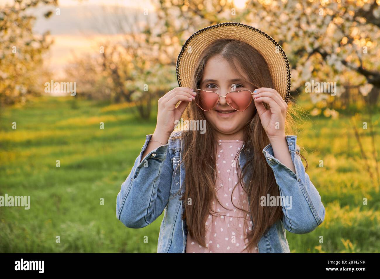 Kleines glückliches Mädchen in einem Hut in einem schönen Frühlingsgarten. Stockfoto