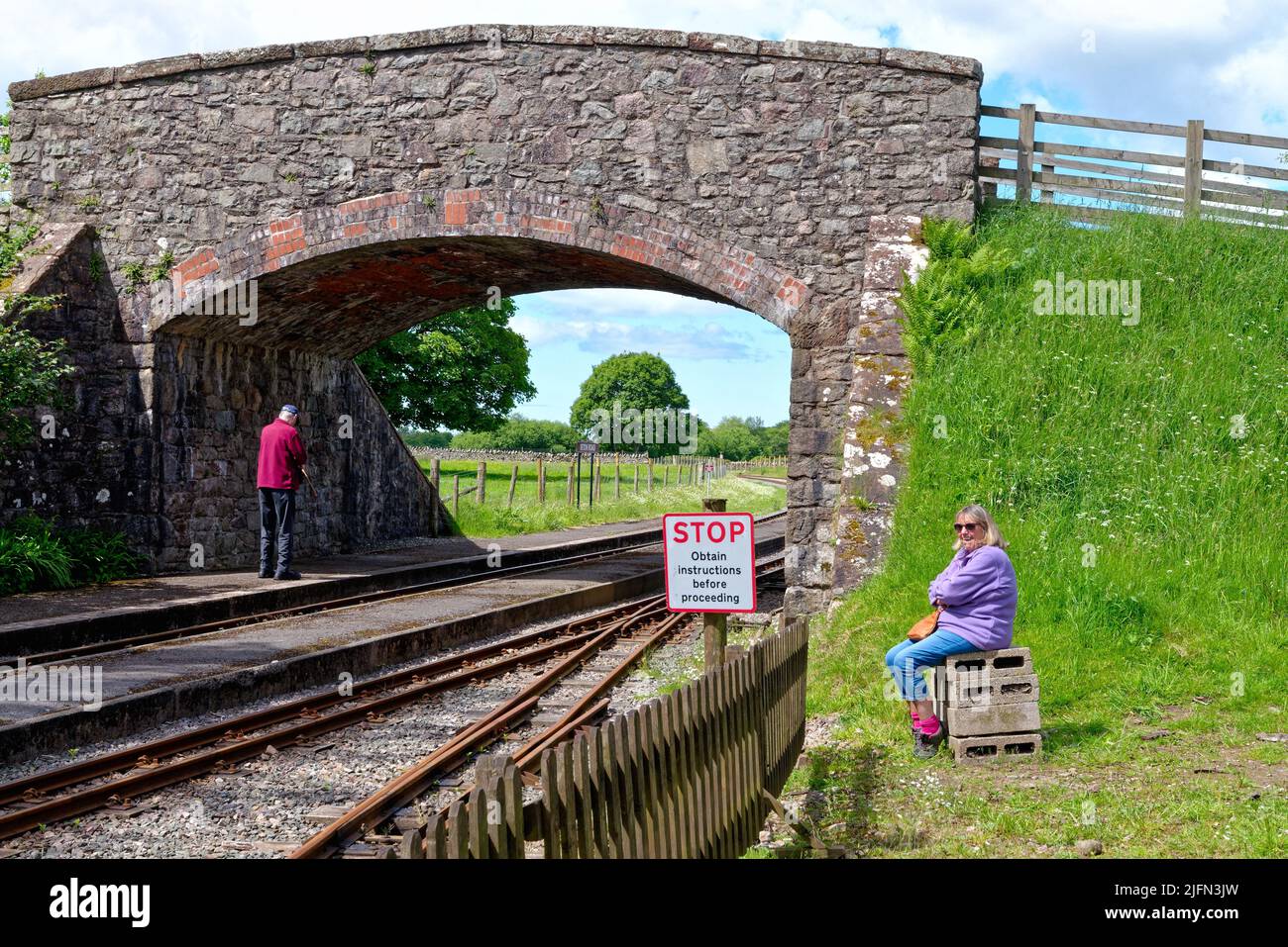 Eine Frau mittleren Alters wartet auf einen Zug am Irton Road Station auf der Ravenglass und Eskdale Railway am Eskdale Green Lake District Cumbria England Stockfoto