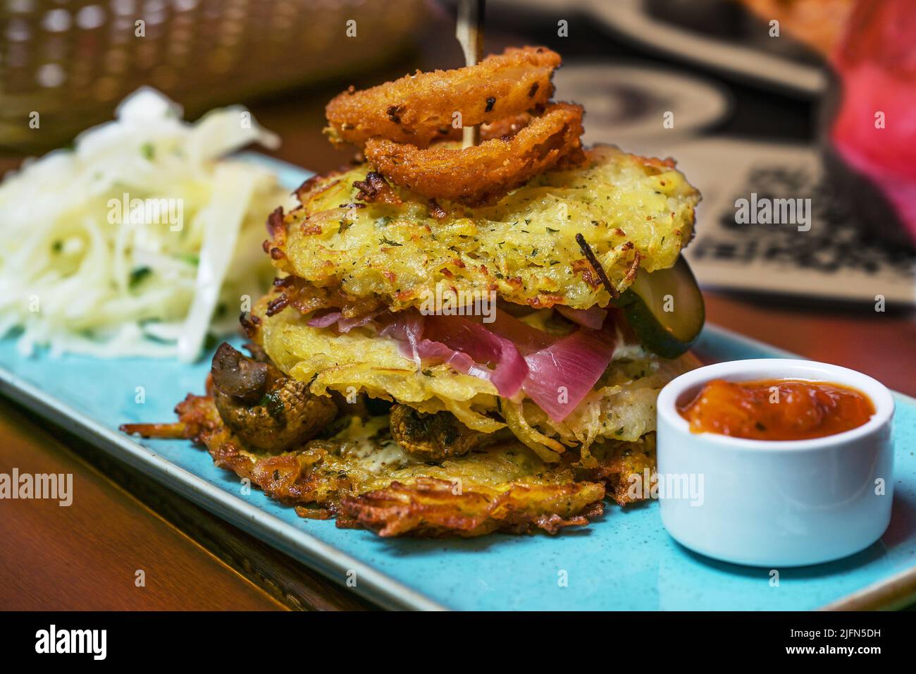 Stapel Kartoffelpfannkuchen gefüllt mit Zwiebeln und Pilzen, serviert mit heißer Sauce und Salat, ausgewählter Fokus, enge Schärfentiefe Stockfoto