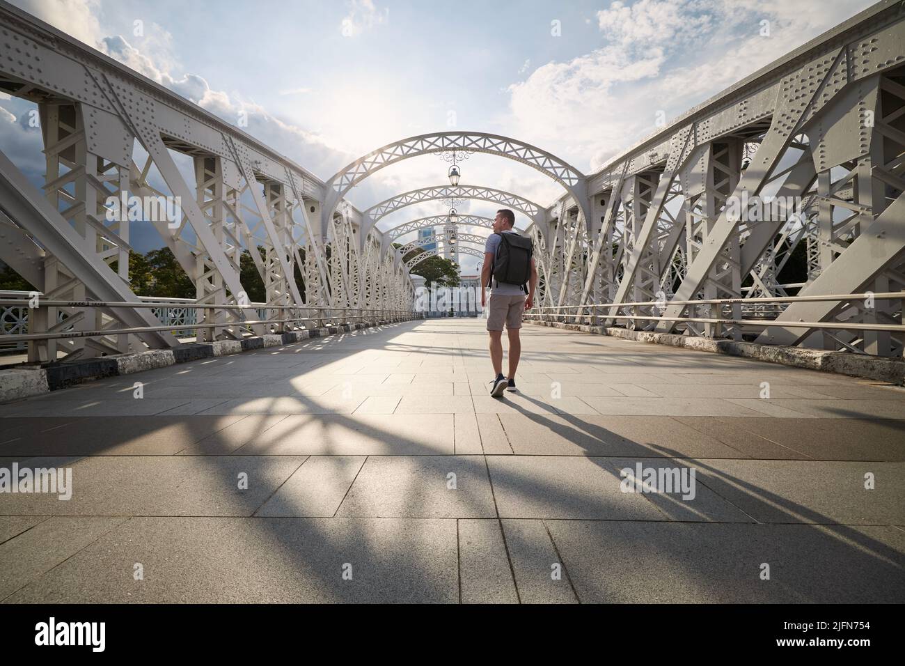 Rückansicht eines Mannes mit Rucksack beim Spaziergang auf der historischen Stahlbrücke in der Innenstadt von Singapur. Stockfoto