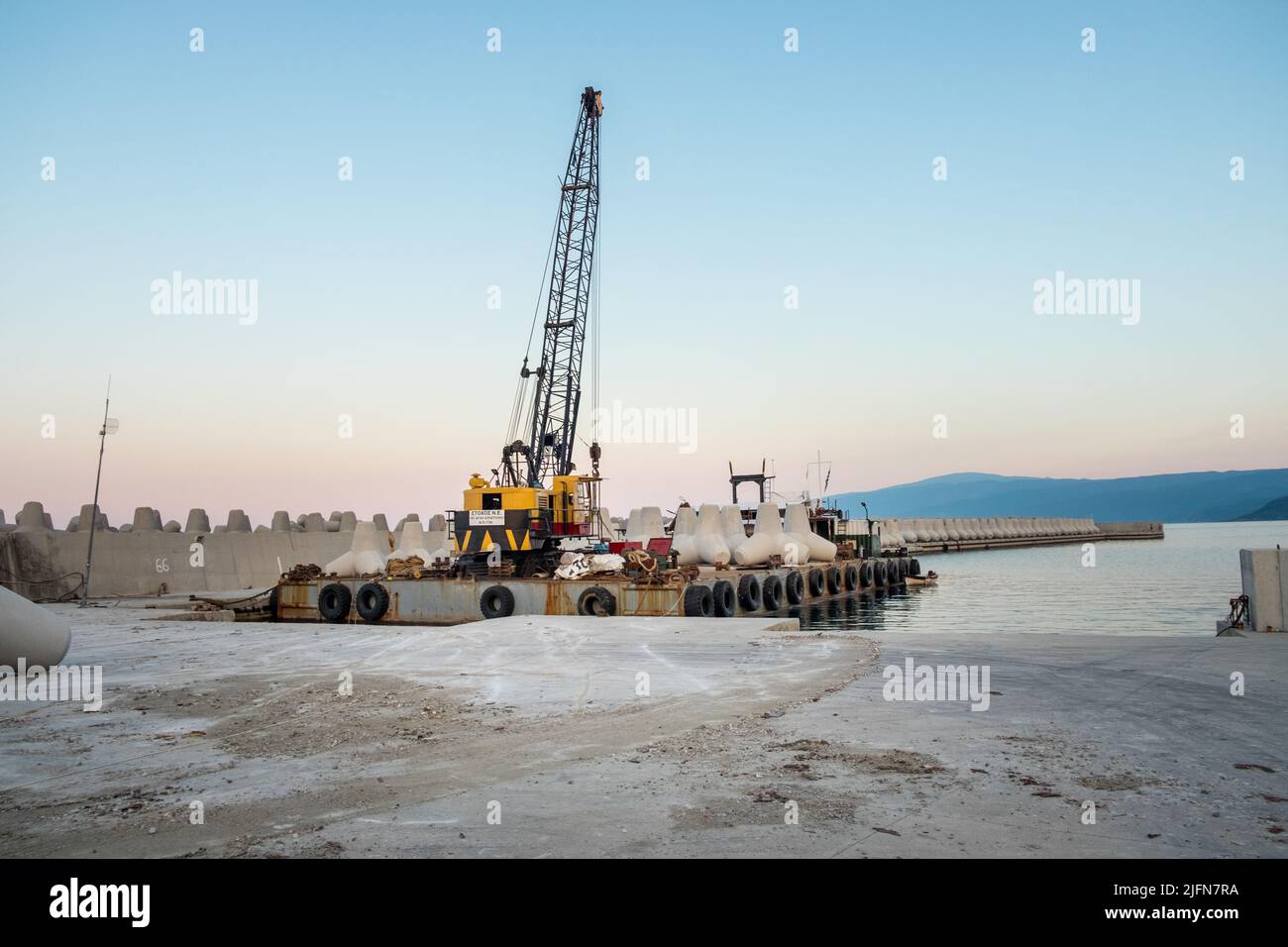 Kranwagen und Wellenbrecher in einem Hafen Stockfoto