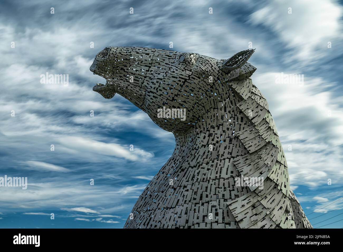 Falkirk, Vereinigtes Königreich - 20. Juni 2022: Eine der Kelpies-Pferdekopfskulpturen mit einem ausdrucksstarken, langbelichteten Himmel dahinter Stockfoto