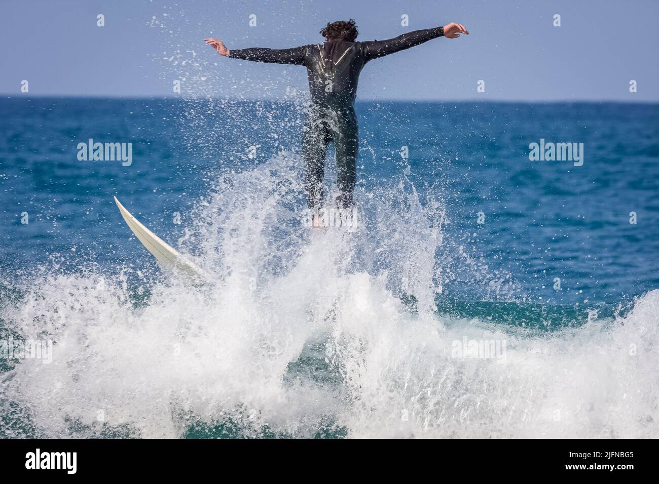 Ein Surfer, der in Jeffreys Bay, Südafrika, auf einer Punktebrecherwelle reitet und abwischend ist Stockfoto