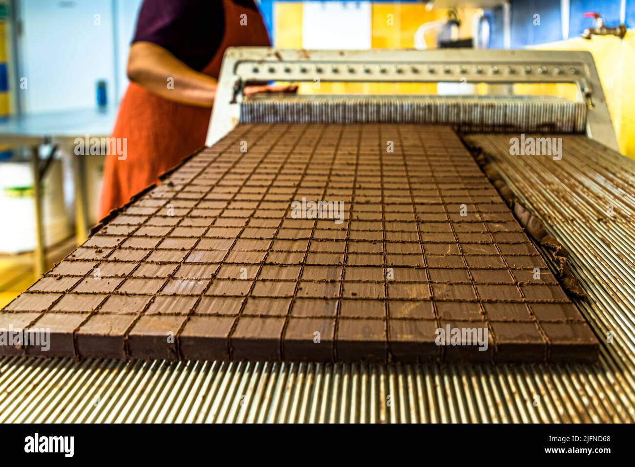 Schneiden der Nougat-Pralinen in der Chocolaterie Frigoulette. Die geschnittene Praline kommt ohne zusätzliche Schokoladenschale. Bei der Herstellung aus Beaufort-sur-Gervanne (die, Frankreich) werden ausschließlich zertifizierte Bio- und Fairtrade-Kakaobohnen aus Sao Tomé verwendet. Stockfoto