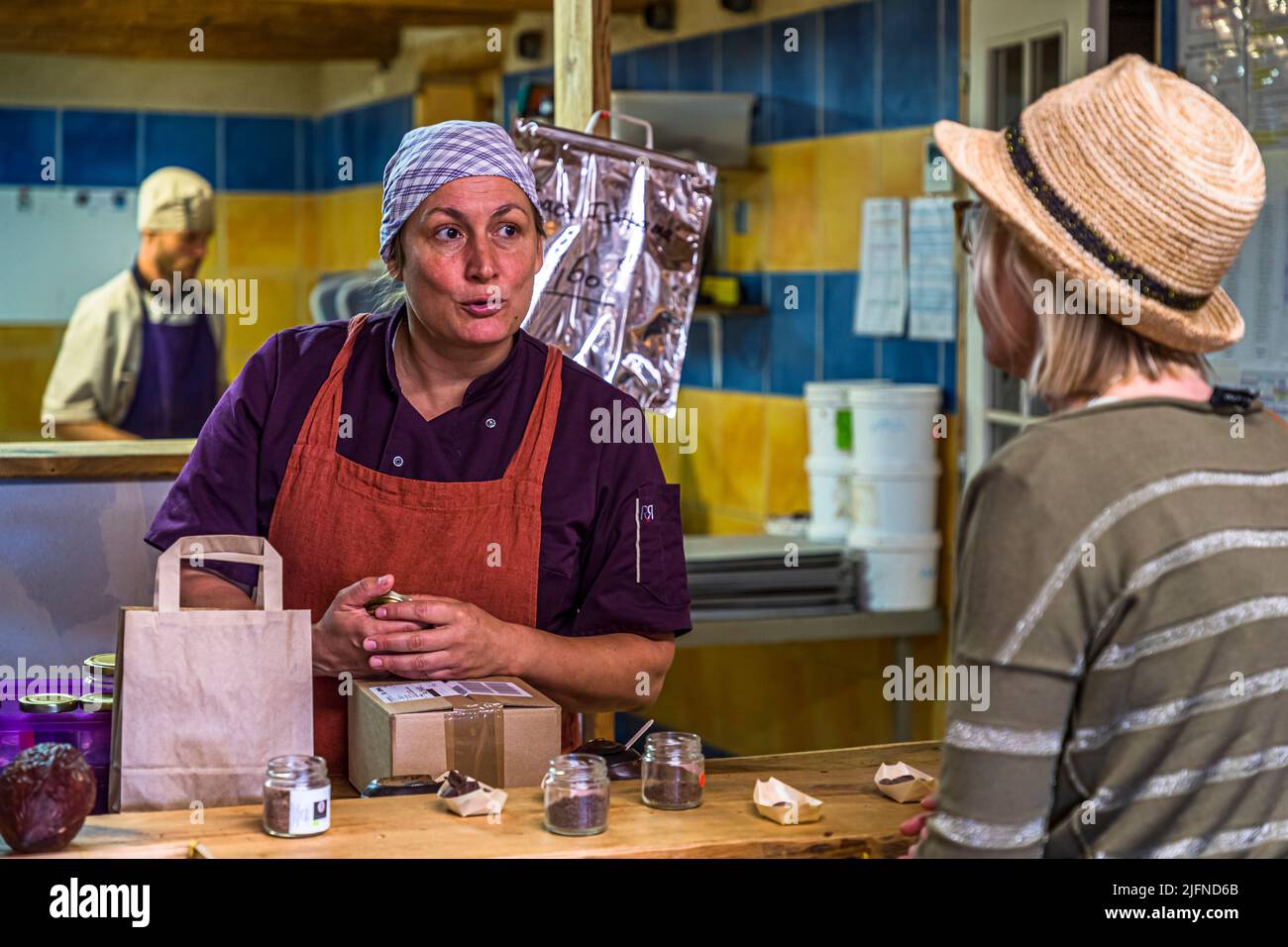 Einkaufen in der Chocolaterie Frigoulette in Beaufort-sur-Gervanne (die, Frankreich). In der offenen Küche im Hintergrund werden bereits Nougat-Pralinen für Weihnachten im Sommer hergestellt. Die, Frankreich Stockfoto
