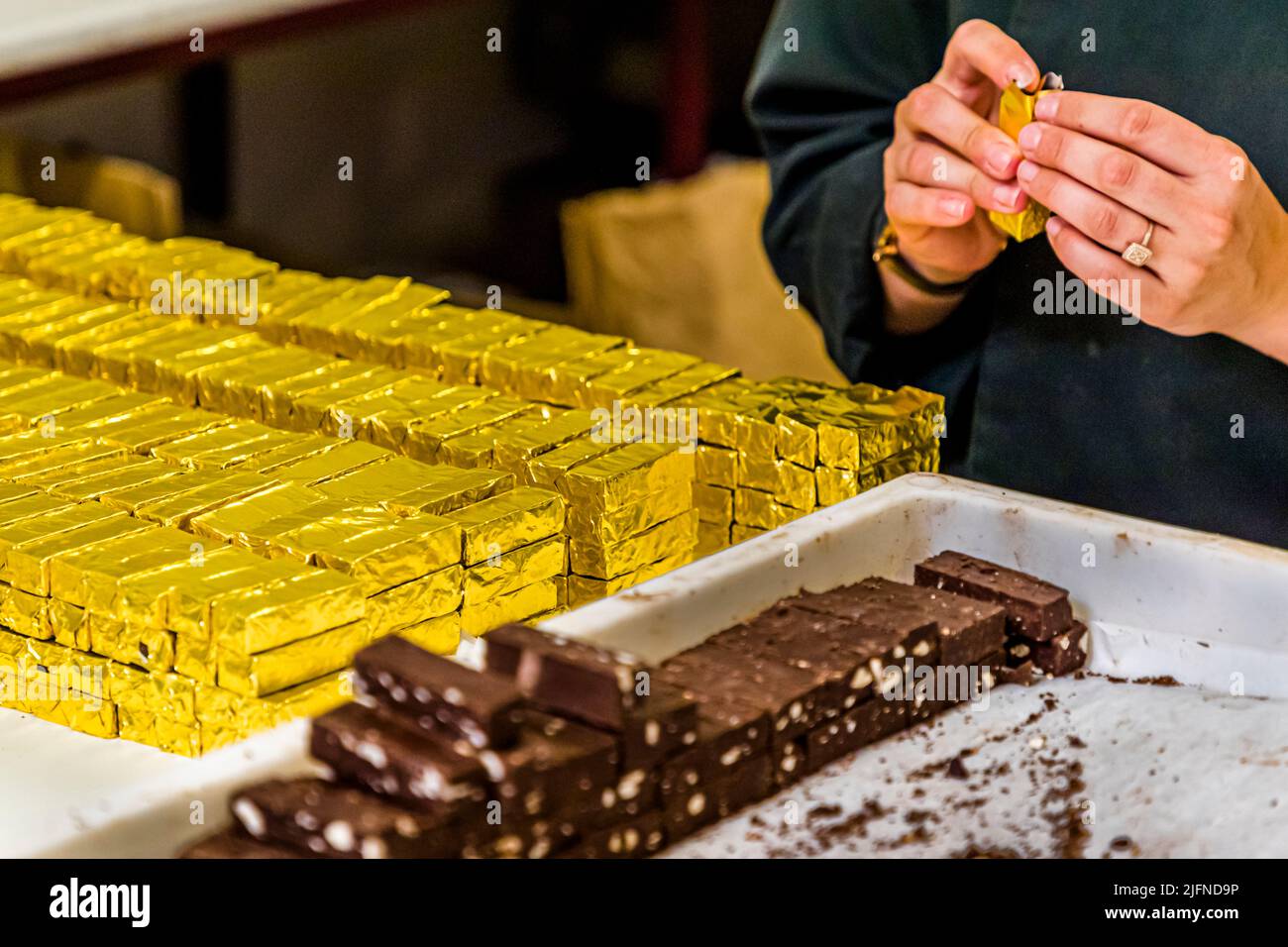 Handgefertigt, ist der Bestseller der Schokoladenmanufaktur Frigoulette in goldenes Papier gewickelt. Die Malakoff-Praline aus der Chocolaterie Frigoulette ist in ganz Frankreich erhältlich und besonders zu Weihnachten beliebt. Malakoff ist eine dieser in Scheiben geschnittenen Pralinen, die keine zusätzliche Verpackung in der Mitte haben. Die gerösteten Haselnüsse verleihen der Praline eine knusprige Textur Stockfoto