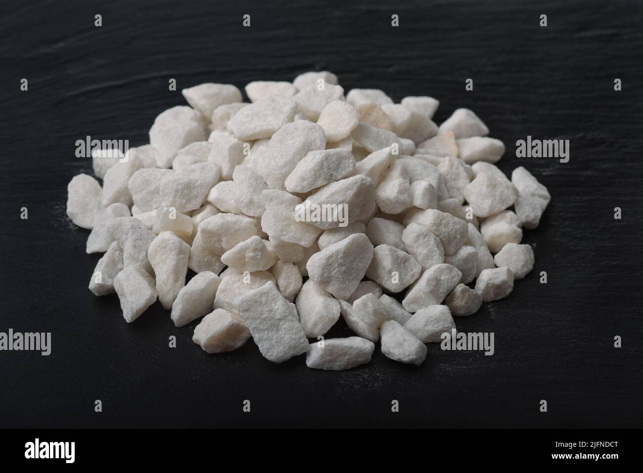 Stapel von natürlichen zerkleinerten Marmorspäne auf schwarzer Steinoberfläche Stockfoto