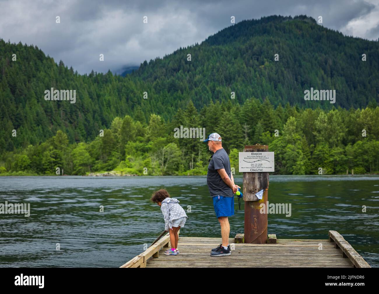 Enkelin und ihr Großvater spielen auf dem See im Park. Großelternteil mit Enkelkind, das gemeinsam am See Spaß hat. Reisefoto, selektiv Stockfoto