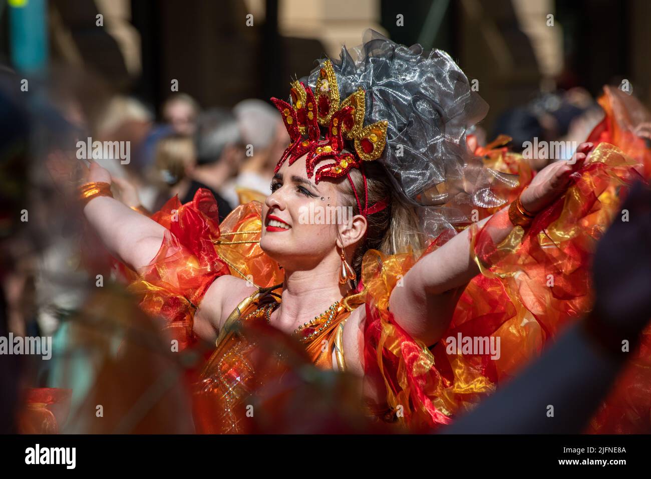 Weibliche Darstellerin in extravaganten orangefarbenen Kleidern bei der Samba Carnaval Parade in Helsinki, Finnland Stockfoto