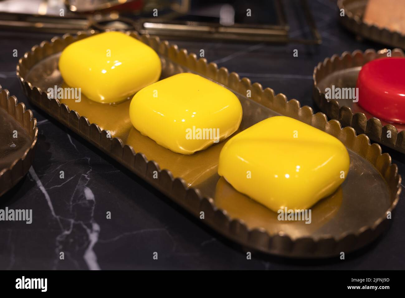 Drei quadratische Kuchen auf einem Tablett mit gelber Vereisung. Stockfoto