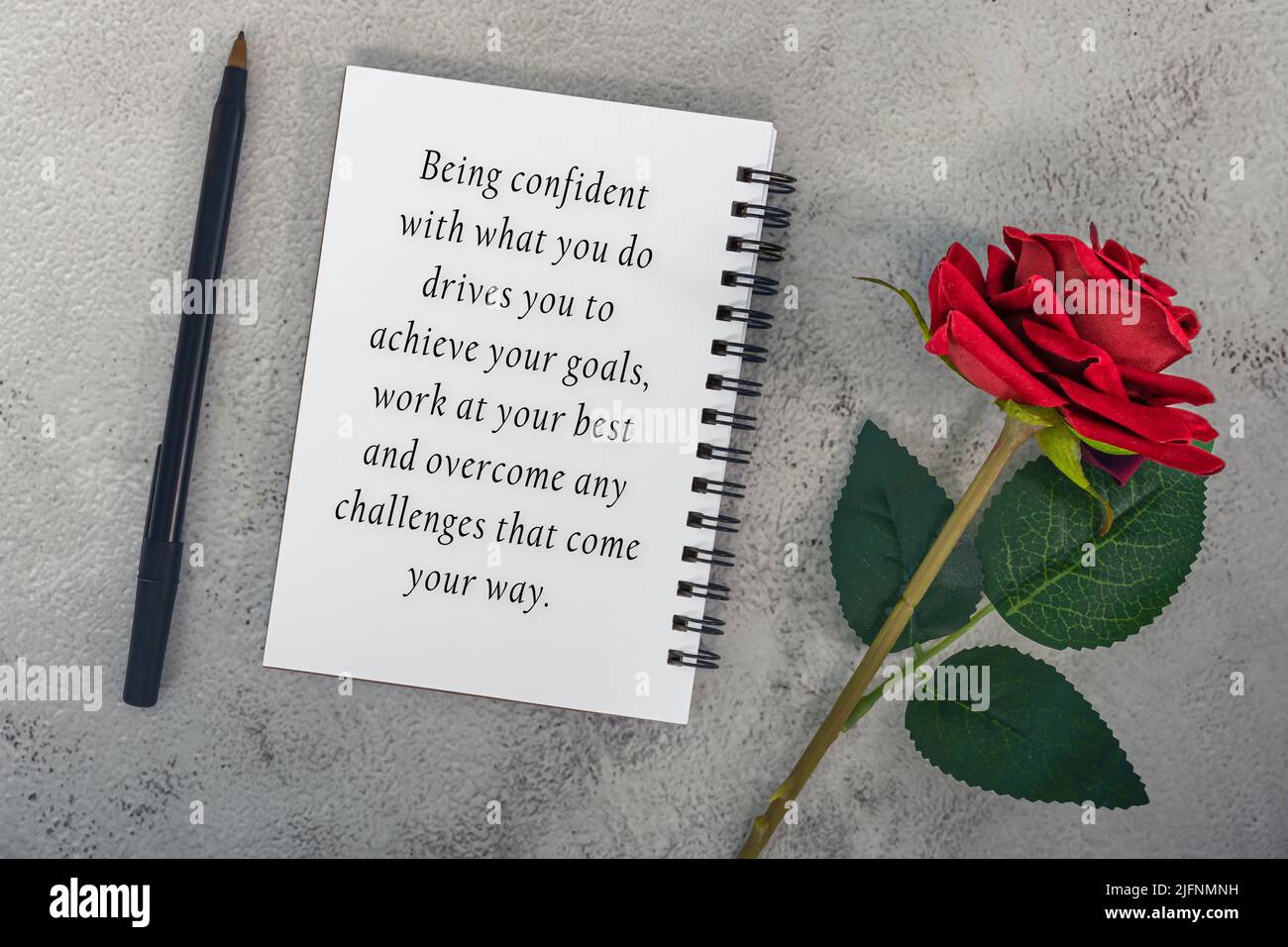 Motivierendes Zitat auf Notiz Buch mit roten Rosen und einem Stift - selbstbewusst mit dem, was Sie tun, treibt Sie, um Ihre Ziele zu erreichen, arbeiten Sie am besten und OV Stockfoto