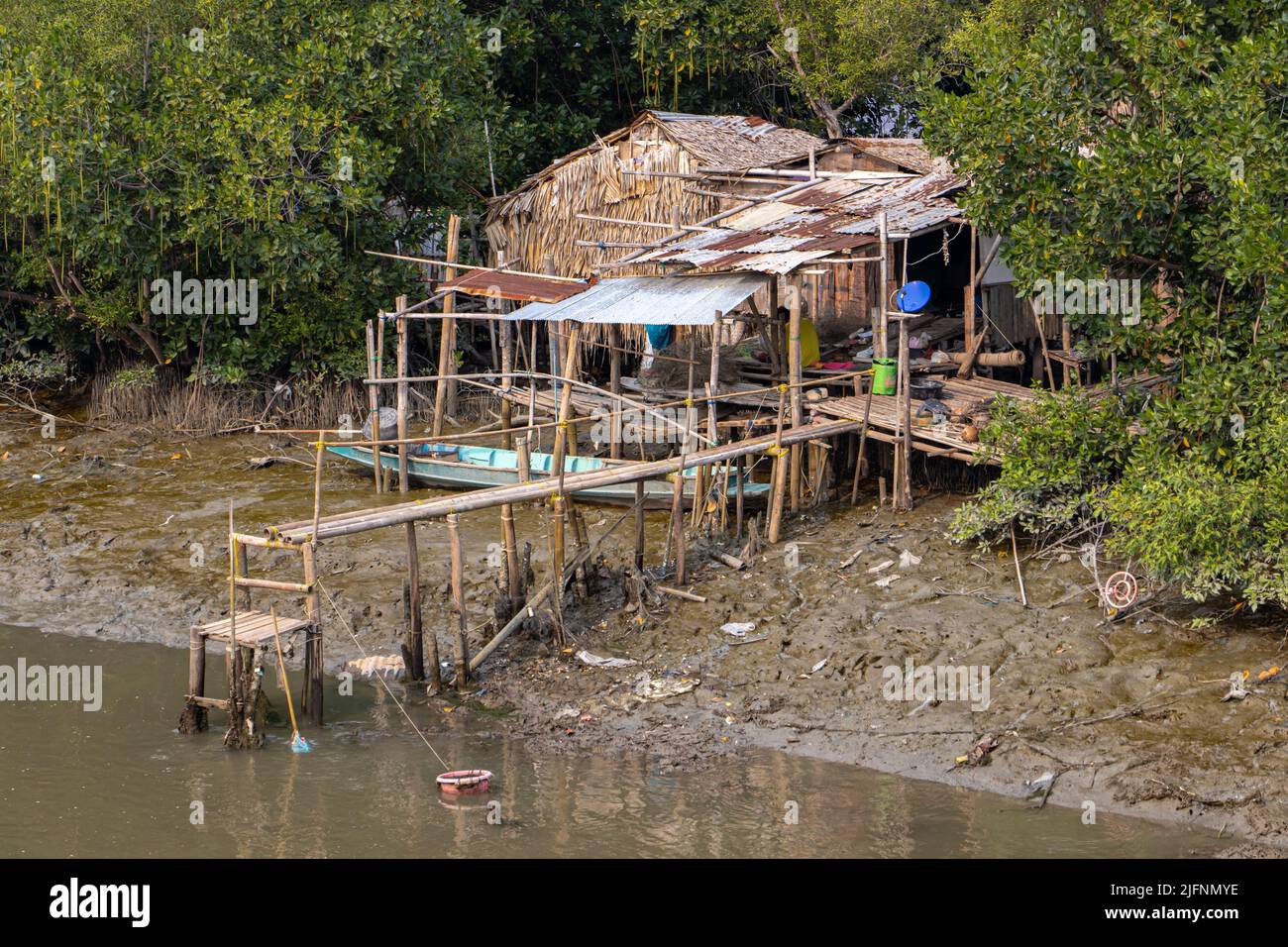 Ein einfaches Haus an einem schlammigen Flussufer. Stockfoto