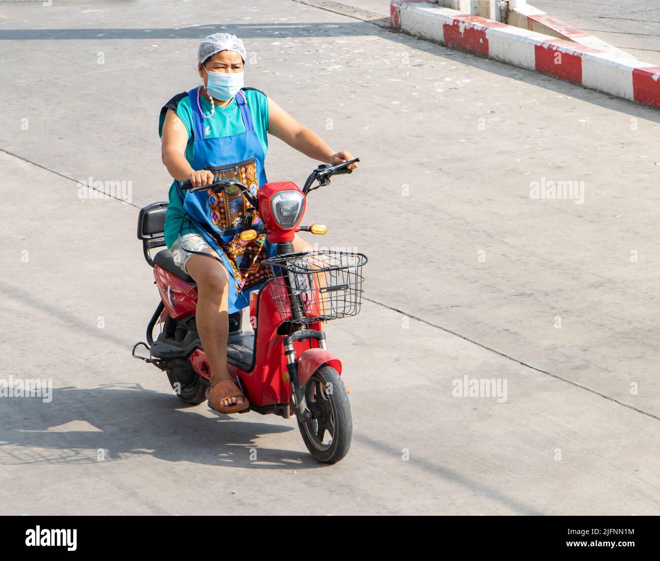 SAMUT PRAKAN; THAILAND; APR 15 2022; Eine Frau fährt auf einem Elektroroller Stockfoto