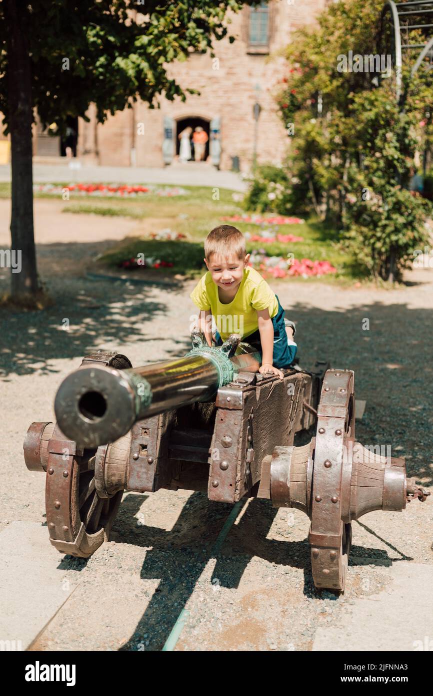 Ein kleiner Junge sitzt auf einer historischen Kanone Stockfoto