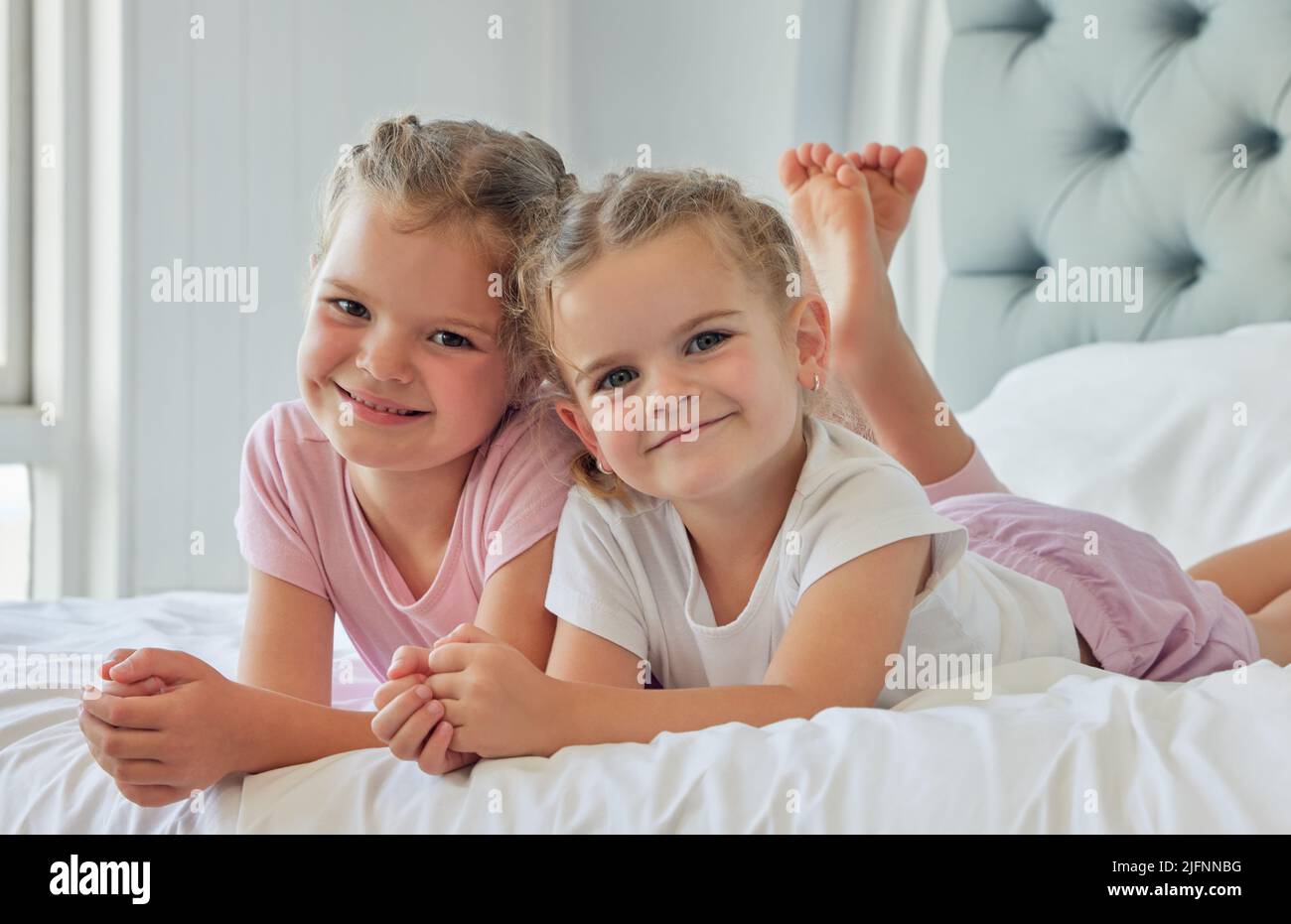 Porträt von Geschwistern, die zusammen spielen. Zwei kaukasische Mädchen entspannen sich zusammen. Schwestern verbringen Zeit miteinander in ihrem Schlafzimmer. Kleine Mädchen zusammen bei Stockfoto
