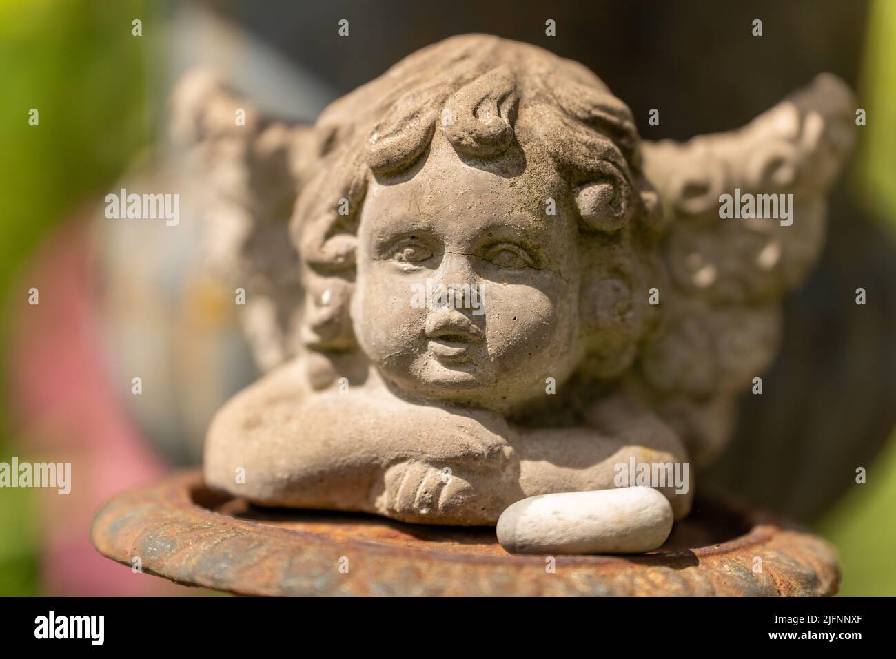 Eine Nahaufnahme der süßen Engelsstatue des Cherubs auf unscharfer Hintergrundkulisse Stockfoto