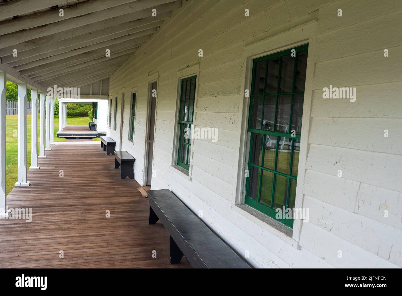 Bank auf der überdachten Veranda und Gebäude im Fort Wilkins Historic State Park Stockfoto