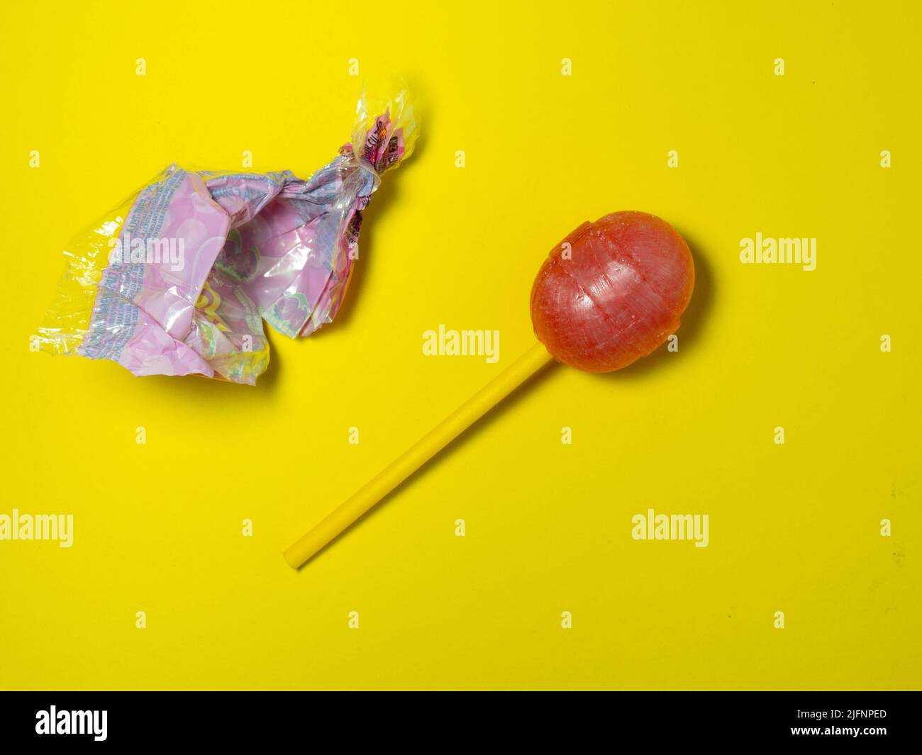 Ungewickelte Süßigkeiten. lollipop auf gelbem Hintergrund. Karamell auf einem Stock. Nicht gesundes Essen. Zuckerwatte. Stockfoto