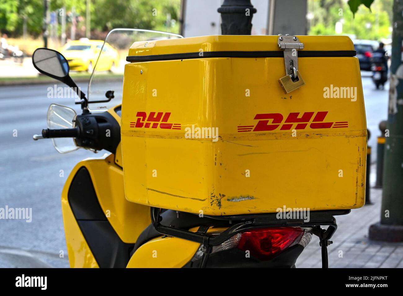 Athen, Griechenland - 2022. Juni: Container auf der Rückseite eines Motorrollers eines Kuriers mit dem DHL-Logo. Stockfoto