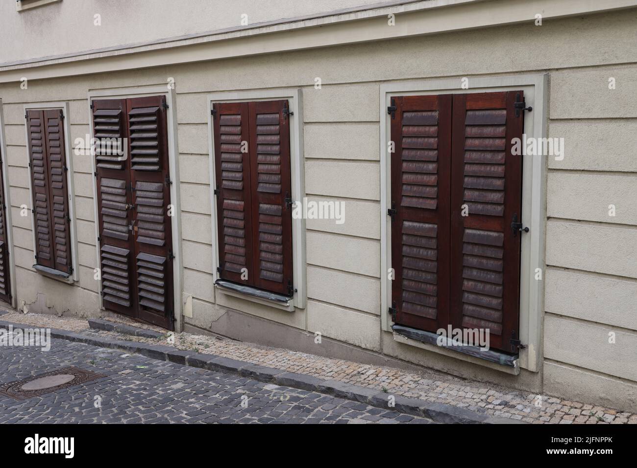 Fassade des Gebäudes mit geschlossenen dunklen hölzernen Fensterläden vor Türen und Fenstern auf einer Straße in Bratislava; geschlossenes Konzept Stockfoto
