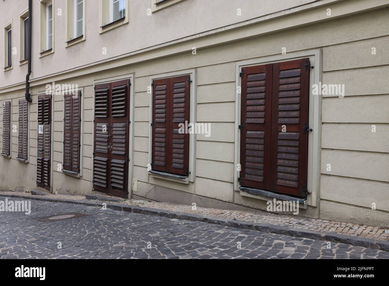 Fassade des Gebäudes mit geschlossenen dunklen hölzernen Fensterläden vor Türen und Fenstern auf einer Straße in Bratislava; geschlossenes Konzept Stockfoto