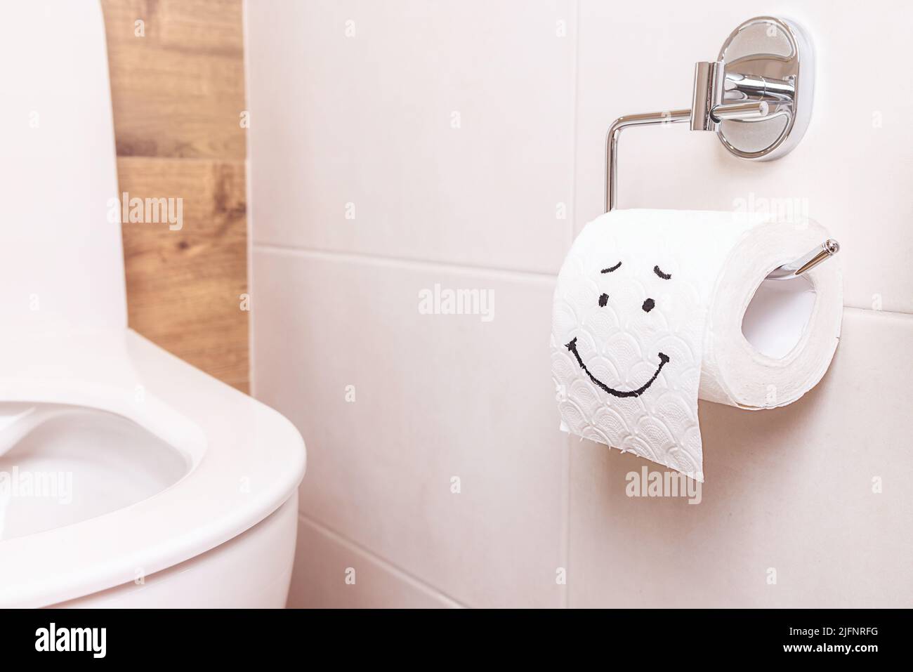 Eine Rolle Toilettenpapier mit einem fröhlichen Gesicht hing an einer  weißen Wand im Badezimmer Stockfotografie - Alamy