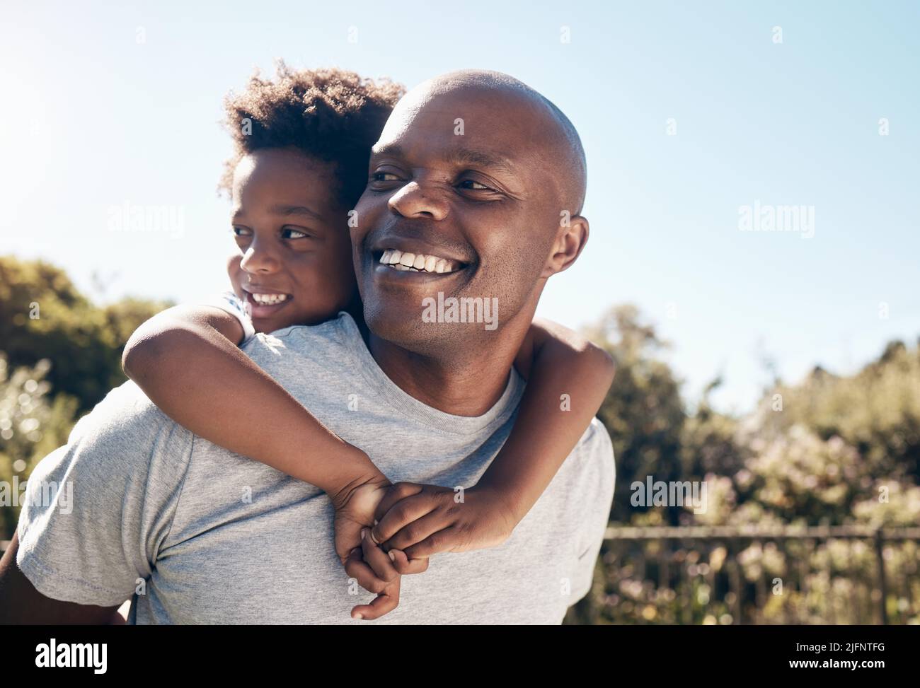 Nahaufnahme eines glücklichen afroamerikanischen Mannes, der sich draußen mit seinem kleinen Jungen verbunden hat. Zwei schwarze männliche Vater und Sohn schauen glücklich und positiv während Stockfoto