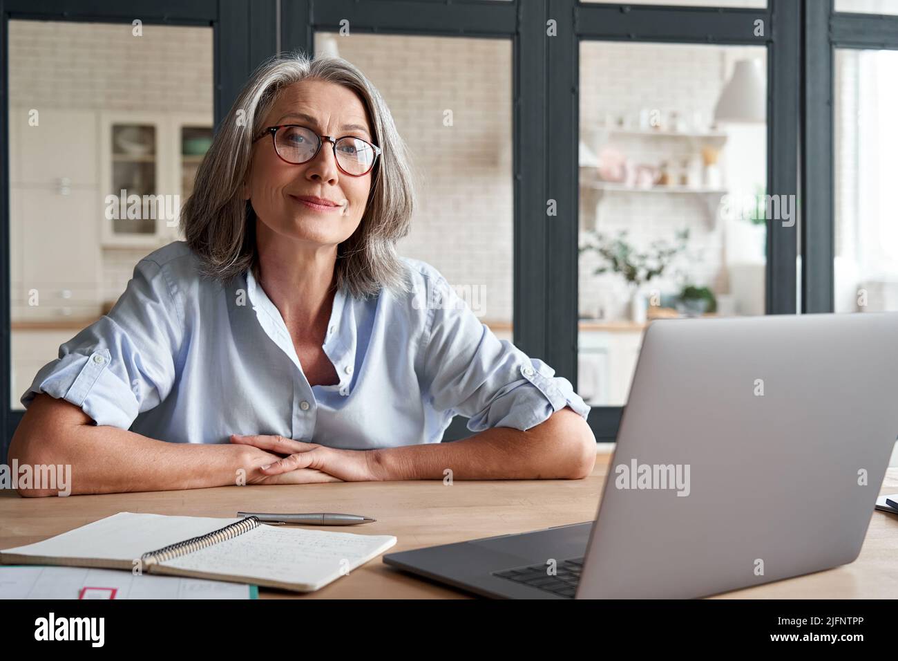 Lächelnd reife Frau mittleren Alters sitzt am Arbeitsplatz mit Laptop, Porträt. Stockfoto