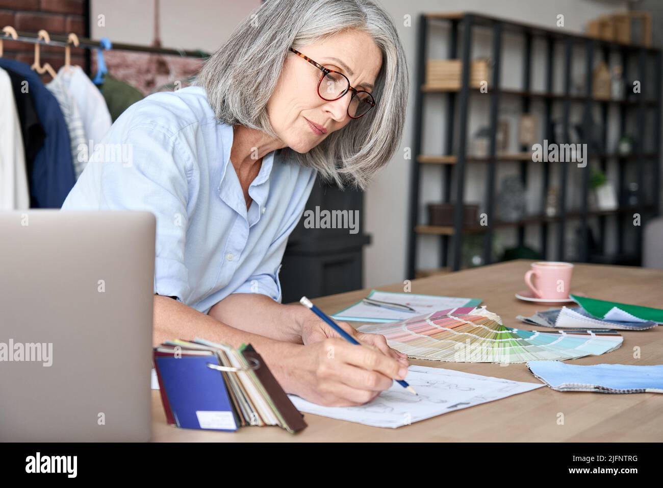 Leitender Modedesigner mittleren Alters, der im Modedesignstudio arbeitet. Stockfoto