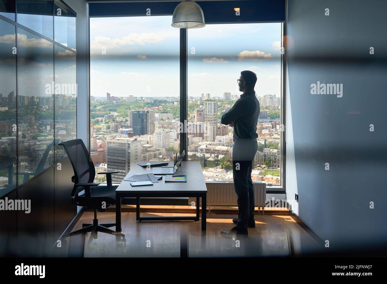 Silhouette eines Geschäftsmannes, der im Büro mit Blick auf die Stadt der Großstadt steht. Stockfoto