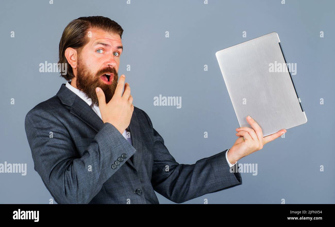 Überraschte Mann mit Laptop-Computer. Geschäftsmann in formeller Anzugkleidung mit Notizbuch. Technologie, Internet. Stockfoto