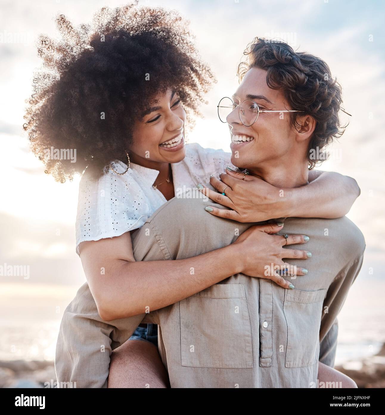 Ein junges gemischtes Paar, das einen Tag am Strand genießt und glücklich und verliebt aussieht. Ein junges gemischtes Rennpaar genießt einen Tag am Strand und sieht glücklich aus Stockfoto