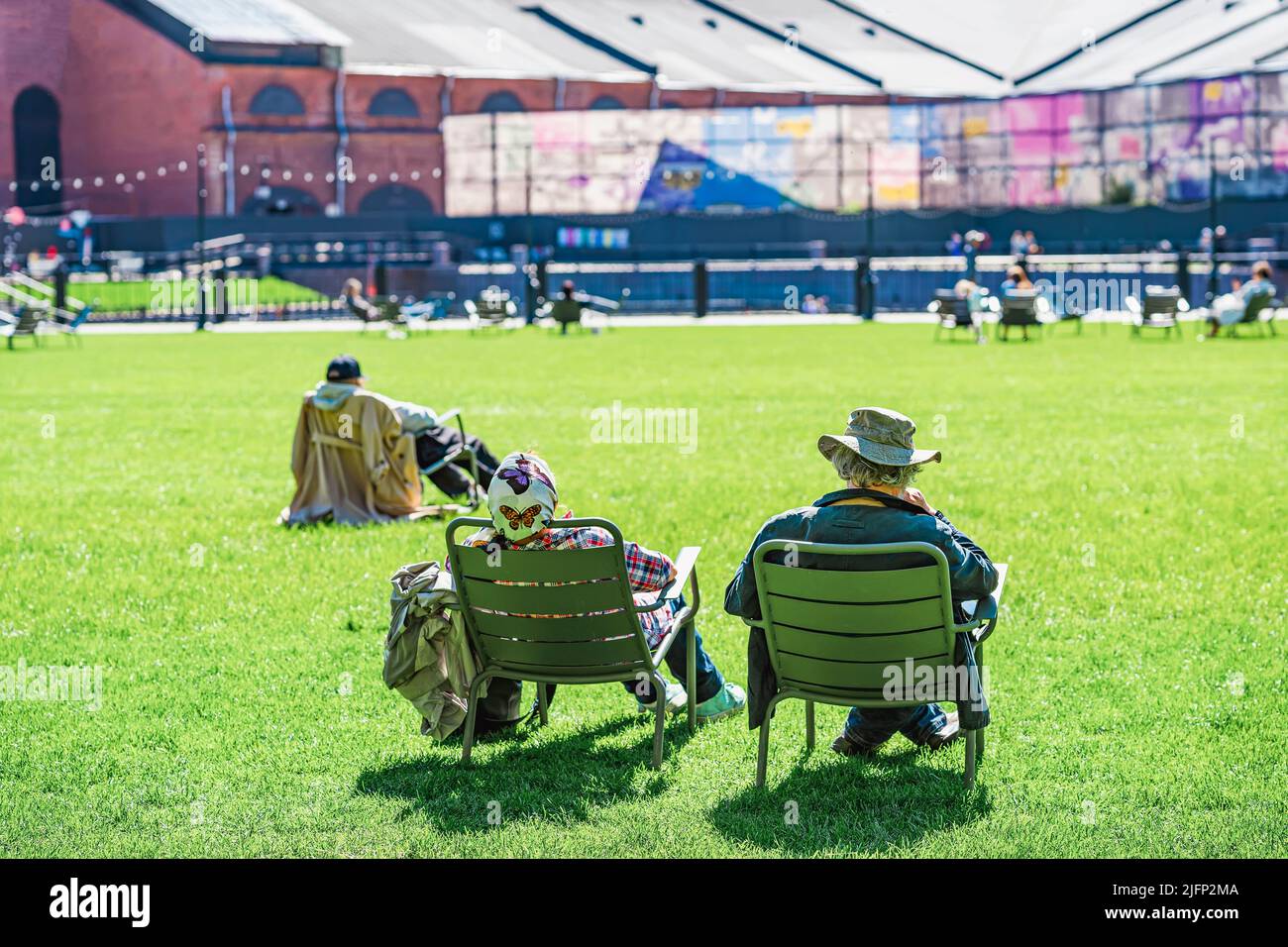 Erholsames Paar, das sich in Sesseln entspannt, zurück zu uns am Frühlingstag auf einer grünen Wiese Stockfoto