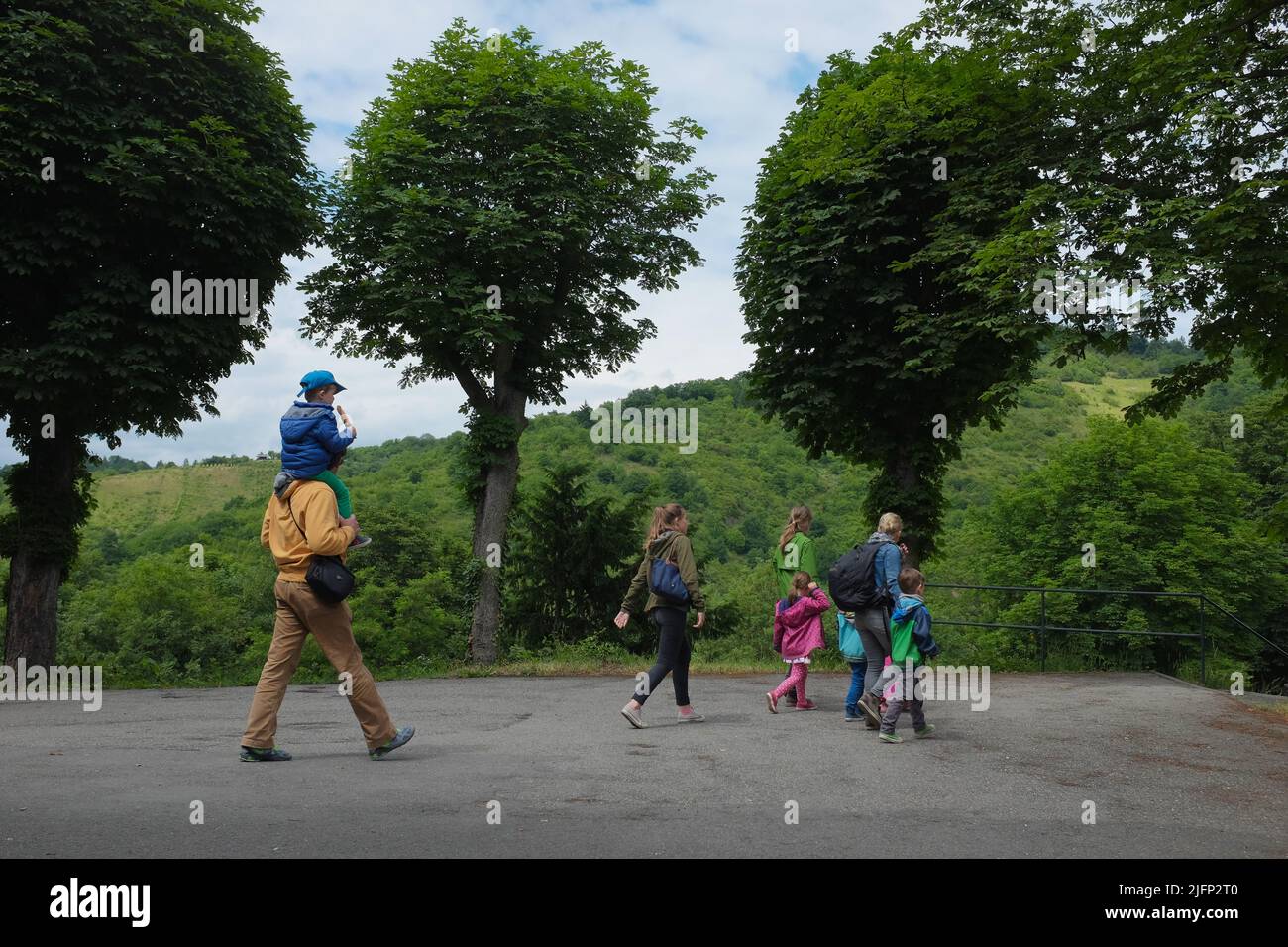 Kaukasische Familie, alle in Mänteln, die durch einen grünen Park spazieren, nachdem sie das gut erhaltene Schloss Marksburg in Braubach besucht haben. Stockfoto