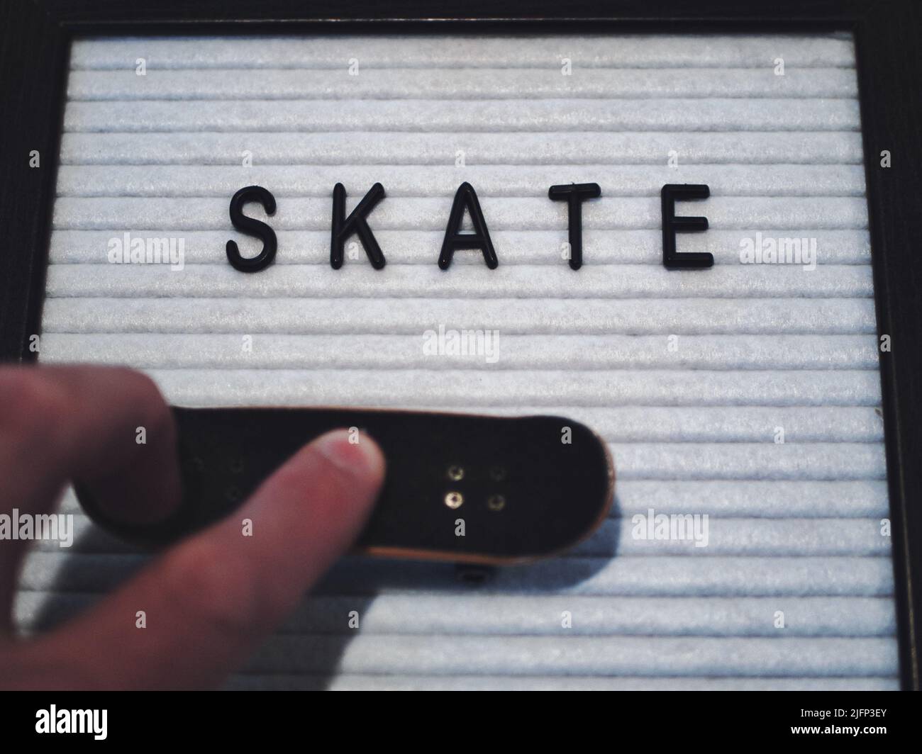 Skate in schwarzem Text. Professioneller Fingerboard-Experte, der einen 360 Kickflip (tre Flip) macht. Lustige Grafik, die Skateboarding in einer lizenzfreien Darstellung illustriert Stockfoto